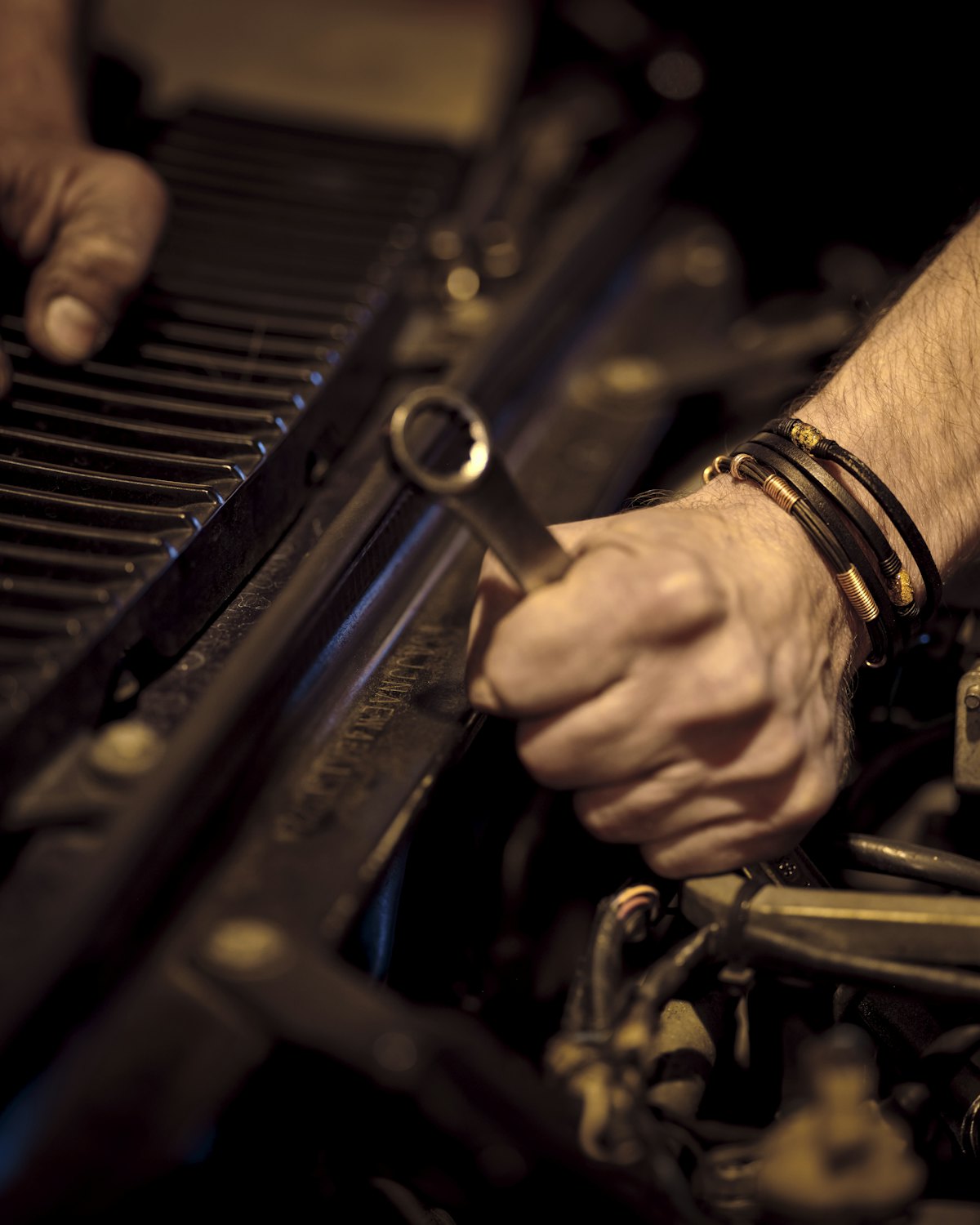 Hand mit Ringschlüssel an einem Automotor